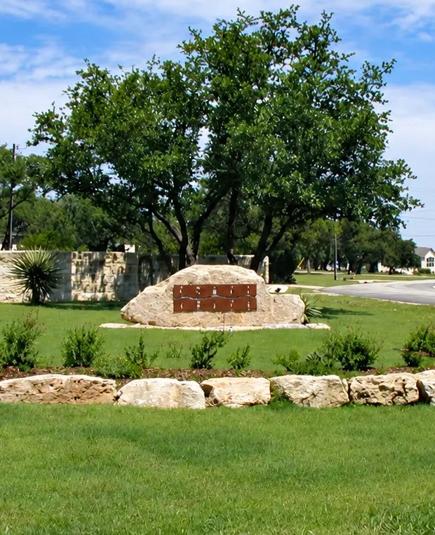 The limestone entrance monument and curving road at Comal Trace